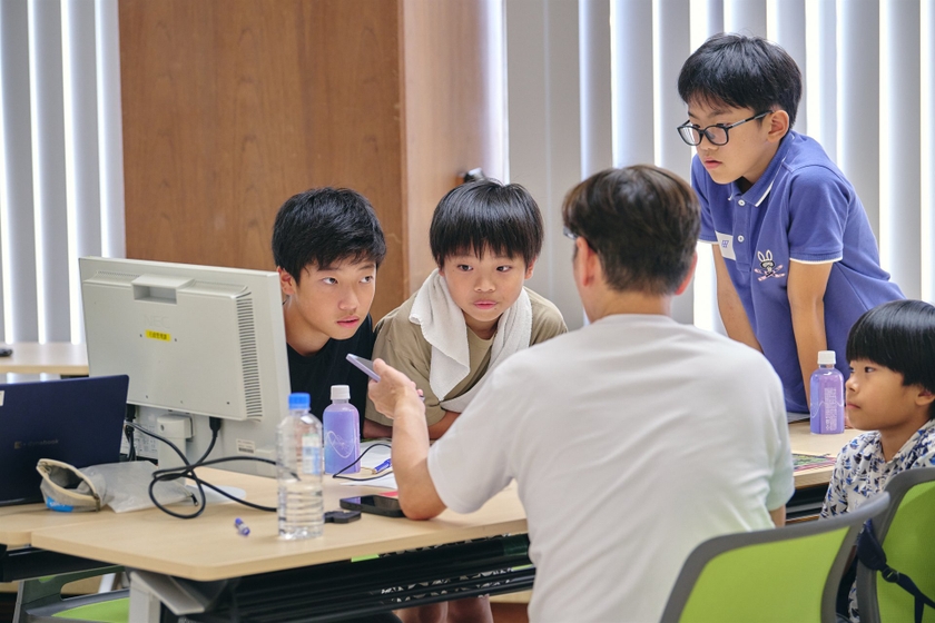 モニターの前でKDDI社員から操作の説明を聞く